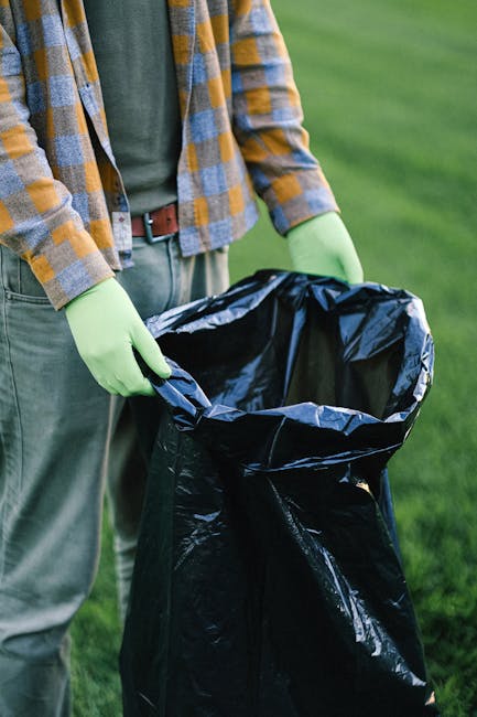 The image shows the rear section of a white commercial van parked on a street or driveway, with three large blue plastic rubbish bags placed on the ground behind it, potentially filled with waste mate